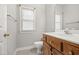 Well lit bathroom with a wooden vanity with white countertop, toilet, and window at 4701 Regalwood Dr, Raleigh, NC 27613