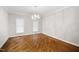 An open dining room with shiny wood floors, white walls, trim, and a decorative light fixture at 4701 Regalwood Dr, Raleigh, NC 27613