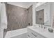 Well-lit bathroom featuring modern gray tile, white vanity, and bathtub with shower at 1000 Addison Pl # 101, Raleigh, NC 27610