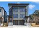 Contemporary townhome featuring a gray facade, black framed windows, attached garages, and manicured landscaping at 1000 Addison Pl # 101, Raleigh, NC 27610