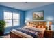 Cozy bedroom featuring a wooden bed frame, blue walls, and natural light from the window at 1212 Southgate Dr, Raleigh, NC 27610