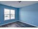 Bedroom features wood-look flooring, a bright window, and painted blue walls at 1212 Southgate Dr, Raleigh, NC 27610