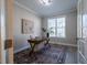 Home office with neutral walls, large windows, a wooden desk, and a patterned rug for a comfortable workspace at 167 Logbridge Rd, Chapel Hill, NC 27516