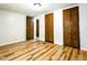 Empty bedroom featuring hardwood floors and three wood paneled closet doors at 1705 Old Nc 10 Hwy, Hillsborough, NC 27278
