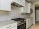 Close-up of kitchen with stainless steel stove, white cabinets, granite counters and subway tile backsplash at 1804 Bright Lantern Way, Wendell, NC 27591