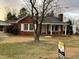 Brick ranch home with covered porch and mature trees. For Sale sign in front yard at 209 N Watauga Ave, Dunn, NC 28334