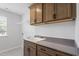 Functional laundry room featuring shaker cabinets, gray countertops, a white sink, and patterned tile floor at 55 New Liberty Dr, Youngsville, NC 27596