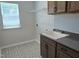 Laundry room with tile flooring, window, and cabinets above sink and countertop at 55 New Liberty Dr, Youngsville, NC 27596