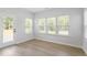 Sun-lit sun room featuring hardwood floors, three windows, and a door leading to an outdoor deck at 55 New Liberty Dr, Youngsville, NC 27596
