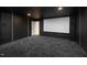 Modern home theater room with a large screen, plush carpet, and dim lighting at 6701 Green Hollow Ct, Wake Forest, NC 27587