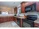 Modern kitchen with dark wood cabinets, black appliances, and a breakfast bar at 6817 Osprey Landing Dr, Wendell, NC 27591