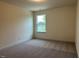 Cozy bedroom showcasing a neutral carpet and a view to the outdoors at 85 Kissington Way, Benson, NC 27504