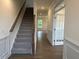 Bright entryway with carpeted stairs, wood handrail, and view into living area at 85 Kissington Way, Benson, NC 27504