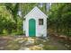 Charming white shed with green door and small window nestled among lush greenery at 1408 Ferrell Ct, Creedmoor, NC 27522