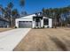 Modern home features a striking gray exterior, complemented by a sleek garage door and manicured landscaping at 145 Ottawa Dr, Louisburg, NC 27549