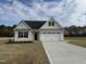 Charming single-story home with a white exterior, black door, and two car garage, set on a sunny lot at 79 Surles Landing Way, Benson, NC 27504