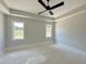 Bedroom featuring tray ceilings and two windows at 130 Broadleaf Ln, Youngsville, NC 27596