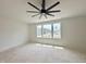 A well-lit, unfinished bedroom with a ceiling fan and multiple windows overlooking a scenic view at 135 Cherry Bark Dr, Youngsville, NC 27596