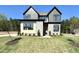 New two-story home featuring stone accents, gray siding, a manicured lawn, and a lush green wooded backdrop at 135 Cherry Bark Dr, Youngsville, NC 27596
