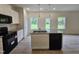 Open concept kitchen boasts white cabinetry, granite countertops, stainless sink in island, black appliances, and wood flooring at 163 Vili Dr, Broadway, NC 27505
