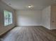 Bright living room featuring wood-look flooring, neutral wall paint, and large windows, next to a white door at 163 Vili Dr, Broadway, NC 27505
