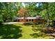Beautiful backyard with well-manicured lawn, mature trees, and a charming brick home at 5205 Rembert Dr, Raleigh, NC 27612