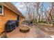 A brick patio features two grills, a fire pit, and an outdoor dining table and chairs with a playset in the yard at 5205 Rembert Dr, Raleigh, NC 27612