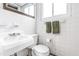 Compact white tiled bathroom featuring a classic sink, toilet, and well-lit with natural light and a mirror at 5205 Rembert Dr, Raleigh, NC 27612