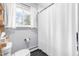 Bright bathroom with a white shower curtain, black tile floors, and a window providing natural light at 5205 Rembert Dr, Raleigh, NC 27612
