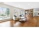 Bright living room featuring hardwood floors, a comfortable couch, and large windows overlooking the backyard at 5205 Rembert Dr, Raleigh, NC 27612