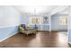 Bright living room with hardwood floors, light blue walls, large windows, and an ornate chandelier at 5205 Rembert Dr, Raleigh, NC 27612