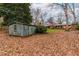 A vintage outdoor storage shed and rear view of home sit amidst mature trees at 5205 Rembert Dr, Raleigh, NC 27612