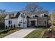 A charming two-story home with stone and white brick exterior, a three-car garage, and a manicured lawn at 1307 Mayfair Rd, Raleigh, NC 27608