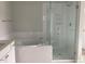 Bright bathroom with soaking tub enclosed in white tile, and glass shower enclosure at 310 N Maple Walk # 236, Garner, NC 27529