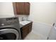 Laundry room features a utility sink with granite countertop, brown cabinets, and a washer and dryer at 109 Springwood Dr, Wake Forest, NC 27587