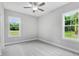 Bright bedroom with grey carpet, ceiling fan, and two large windows at 157 Rainbow Dr, Dunn, NC 28334