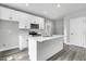 White kitchen with island, stainless steel appliances, and gray vinyl plank flooring at 157 Rainbow Dr, Dunn, NC 28334