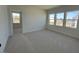 A living room featuring neutral walls, neutral carpet, and multiple windows overlooking the yard at 467 Ravensworth Dr, Garner, NC 27529