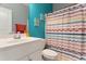This bathroom includes a white vanity, toilet, mirror, and a colorful striped shower curtain at 58 Northview Dr, Middlesex, NC 27557