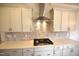 Close-up of kitchen with stainless steel range hood, gas cooktop, stylish cabinets and backsplash at 60 Accord Dr, Youngsville, NC 27596