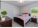 Cozy bedroom with a dark wood bed, soft pink bedding, and a view of the outdoors at 68 Streamline Ct, Lillington, NC 27546