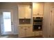 Kitchen with stainless steel double oven, white cabinets, stone backsplash and exterior door to backyard at 70 Accord Dr, Youngsville, NC 27596