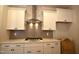Close-up view of the kitchen with stainless steel range hood, gas range, white cabinets, and tile backsplash at 70 Accord Dr, Youngsville, NC 27596