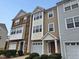 Three-story townhome with stone and siding, two-car garage, and landscaping at 1527 Haywards Heath Ln, Apex, NC 27502