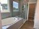 Bright bathroom featuring a tiled tub and a glass-enclosed shower with large window views at 292 Weddington Way, Benson, NC 27504