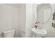 Clean and modern powder room with a pedestal sink, round mirror, and fresh white walls at 620 Brittany Ct, Durham, NC 27703