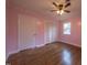 Well-lit bedroom with hardwood floors, ceiling fan, and pink walls at 802 S Sellars Mill Rd, Burlington, NC 27217