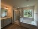 Well-lit main bathroom with tub, shower, double vanity, and a large window with a wooded view at 129 Stallion Way, Benson, NC 27504