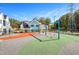 Modern playground with swings and colorful, soft groundcover next to new homes at 144 Weavers Grove Dr, Chapel Hill, NC 27514