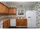 Kitchen with wood cabinets, white appliances, and floral wallpaper at 6409 New Market Way, Raleigh, NC 27615